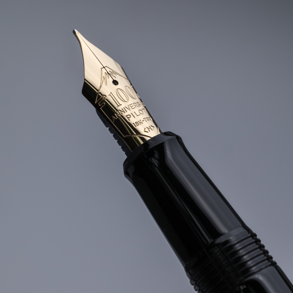 Close-up of a gold Pilot fountain pen nib against a grey background – photography by Filip Labanc for No Smile Needed